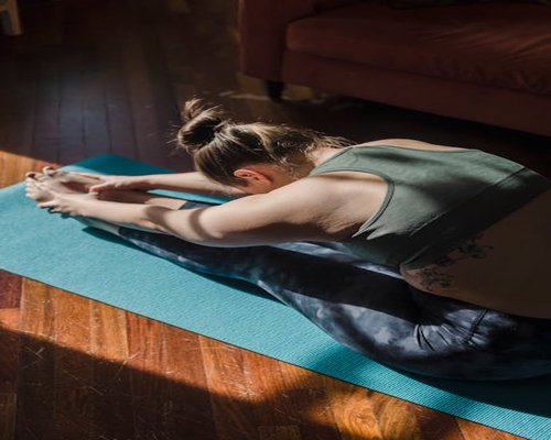 Person doing light stretching exercises at home on a yoga mat