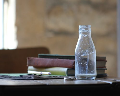 A glass of fresh water on a desk next to a notebook